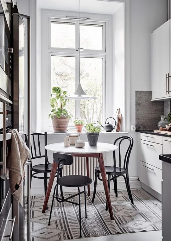 Comedor integrado en la cocina con mesa pequeña redonda y sillas en diferentes estilos